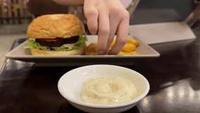 girl eating fast food veggie burger with french fries dipping in sauce and watching video on the internet bad nutrition diet lazy lifestyle restaurant - Powered by Shutterstock - Get 15% off with code: PIKWIZARD15