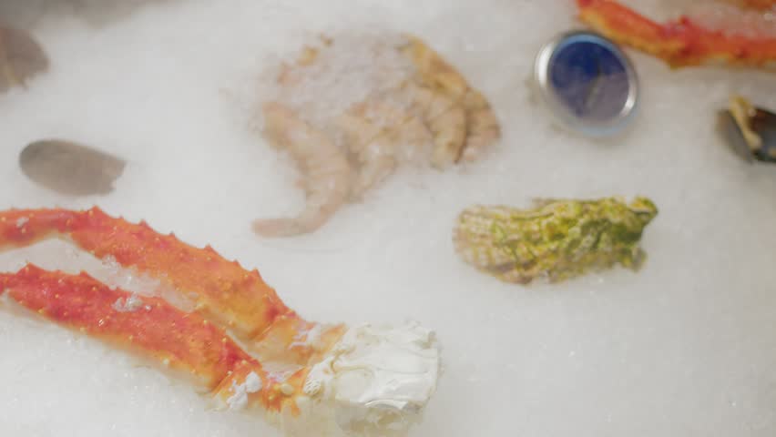 4K Fresh fish, crab, oysters, shrimp are lying in ice.