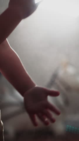 Sportive kid claps hands to shake off talcum powder after punching bag against bright lamp spreading light. Little boy stops boxing in gym closeup slow motion