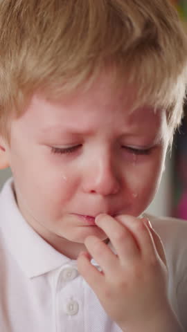 Little boy cries and careful elder sister calms him down in children room closeup. Offended toddler boy with tears on face and loving female sibling