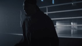 Agile African American guy in hoodie jumps on rope in gym. Young black athlete trains before fighting near boxing ring in club. Leg muscles building routine - Powered by Shutterstock - Get 15% off with code: PIKWIZARD15