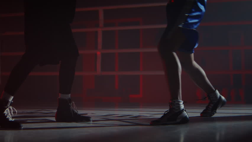 African American sportsmen train fighting together on boxing ring closeup. Strong black athlete with trainer steps fast exercising in semi-dark sports club