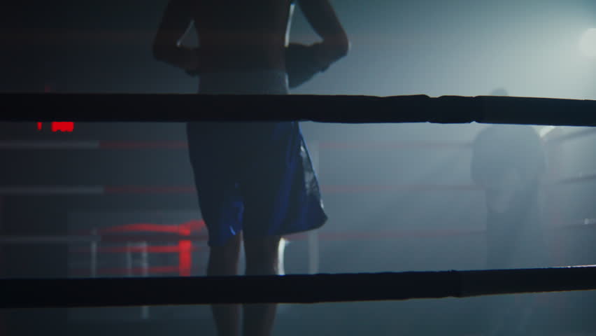 Resolute African American boxer comes on ring through ropes to fight partner. Silhouettes of black sportsmen before sparring in athletic club. Sports activity