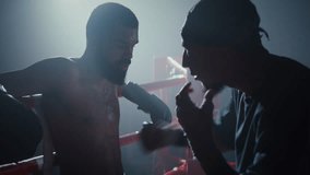 Skilled African American trainer gives advice to boxer leaning onto ring ropes. Silhouette of black man resting while coach explaining fight strategy in gym - Powered by Shutterstock - Get 15% off with code: PIKWIZARD15
