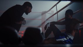 Involved African American instructor helps talk tired sportsman to win fight on ring. Exhausted black boxer sits on floor while trainer advises hits on arena - Powered by Shutterstock - Get 15% off with code: PIKWIZARD15