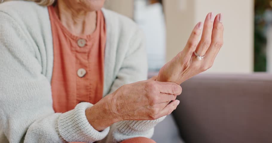 Senior woman, hand pain or injury in living room or couch for relaxing, resting and rubbing for ache relief. Female person, health problem and tension with arthritis or inflammation on sofa at home