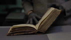An archivist in gloves gently flips through an ancient archival book. Historical document handled with care. Ideal for themes of history, science, preservation, and cultural heritage - Powered by Shutterstock - Get 15% off with code: PIKWIZARD15