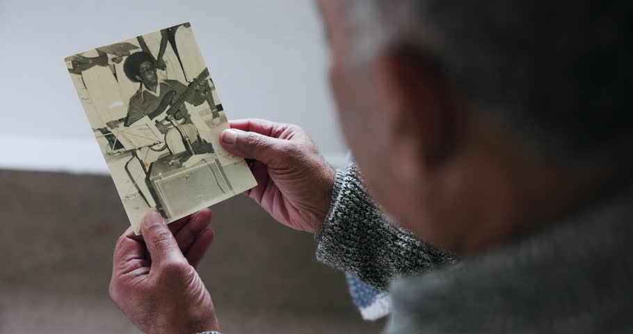History, photography and old man with retirement, hands and thinking with grief, sad and feeling lonely. Pensioner, vintage picture and elderly person with nostalgia, remember and depress in a home