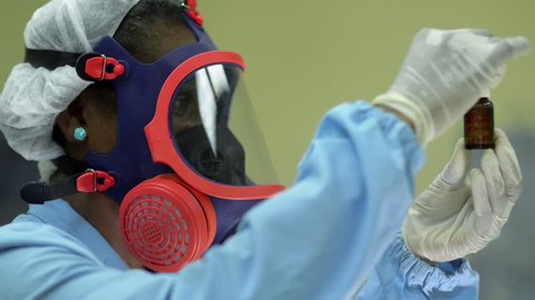 Medical facility and pharmaceutical laboratory with female scientist at work, wearing protective mask for hazardous job and looking at camera. Sequence