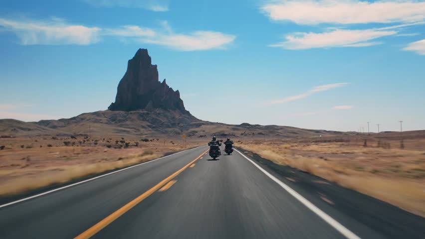 An exhilarating ride showcasing skilled motorcyclists in the stunning landscapes of Monument Valley, Arizona and Utah, with striking rock formations and vast skies enhancing the adventure