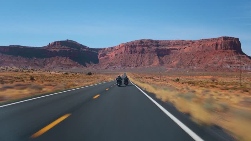 Experience breathtaking views as fearless motorcyclists navigate Arizonas winding roads alongside Utahs Monument Valley, known for its stunning natural scenery that captivates all riders