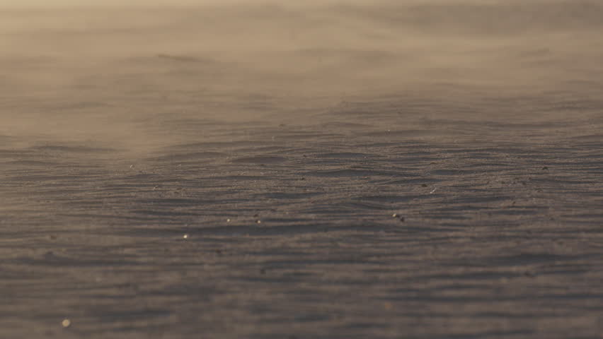 Delicate sand particles drifting across sun drenched textured surface, generating dynamic ripples and intricate wind sculpted patterns in arid landscape