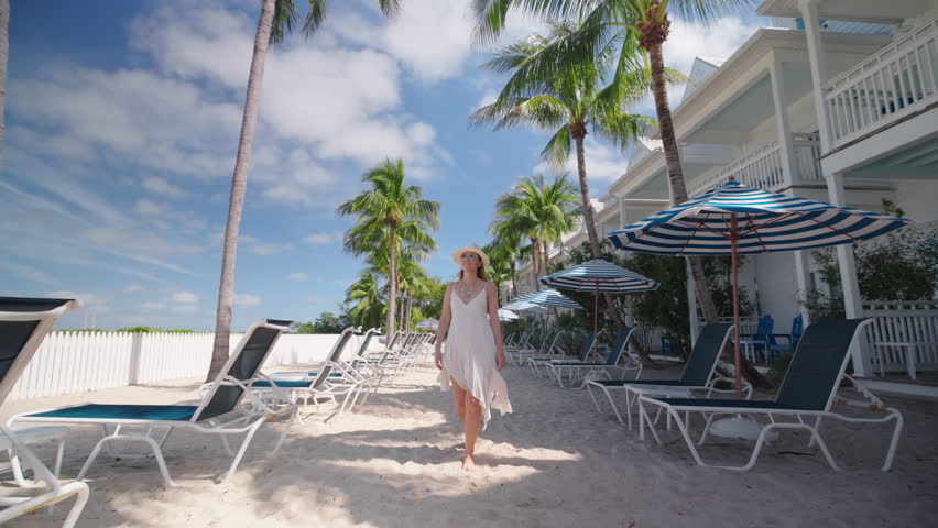 A woman leisurely strolls through a beautifully designed hotel in Key West, Florida, taking a moment to appreciate the calm beauty and serene tranquility that surrounds her during her delightful walk