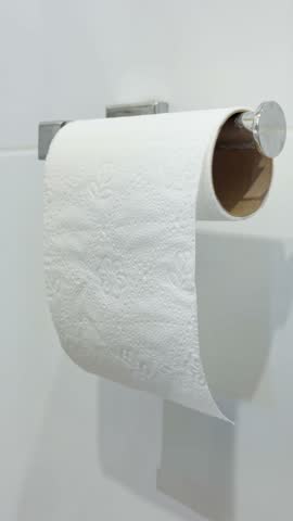 Mans hands taking toilet paper from a wall mounted toilet paper roll