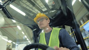 A man in a yellow hard hat and safety vest drives a forklift in a busy warehouse, overseeing the bustling environment. - Powered by Shutterstock - Get 15% off with code: PIKWIZARD15