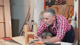 Senior carpenter uses a ruler and set square to measure and assemble a wooden structure with precise alignment, focusing on craftsmanship. Workshop is organized with tools and materials - Powered by Shutterstock - Get 15% off with code: PIKWIZARD15