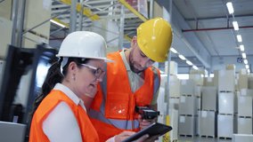 In a warehouse, two workers in hard hats and orange vests collaborate, using a tablet and scanner to manage inventory, ensuring efficient logistics and storage organization. - Powered by Shutterstock - Get 15% off with code: PIKWIZARD15