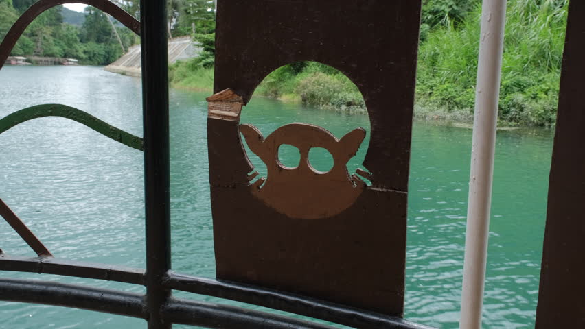 Cruising on a tranquil river in Bohol, surrounded by tropical greenery. A wooden tarsier animal carving adds a touch of local charm to the deck of boat
