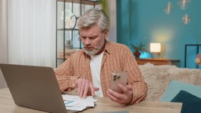 Caucasian mature man at home, using laptop and smartphone, reviewing financial reports. Middle-aged guy appears exhausted, rubbing eyes and diligently trying to find solutions for financial problems - Powered by Shutterstock - Get 15% off with code: PIKWIZARD15