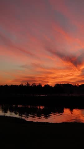 Bright orange sunrise over river and forest. Beautiful morning landscape. Nature background. Vertical video