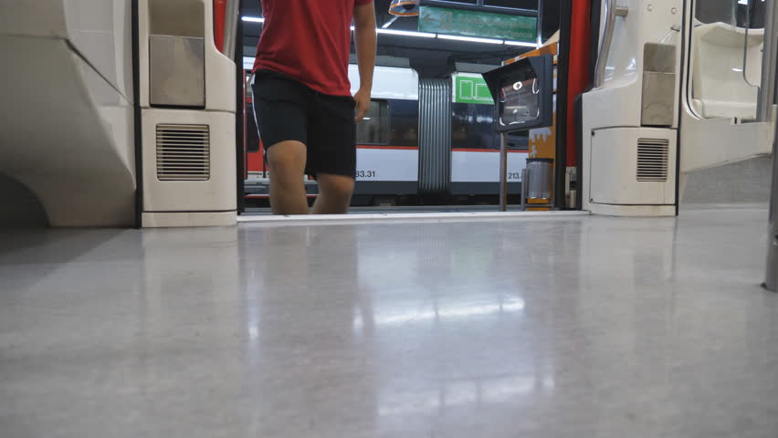 Male legs entering to train doors and going through modern wagon. Feet of young man walking along empty carriage of passenger railway transport. Concept of vacation or holiday. Low view