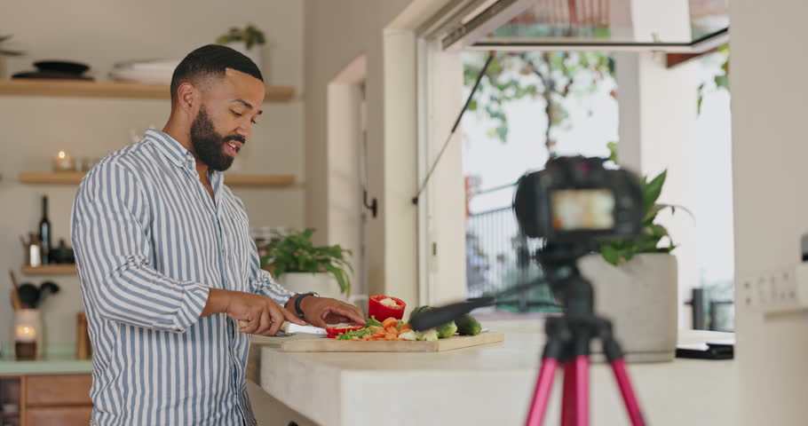 Man, cooking and live streaming with talking in kitchen for video, post or vlog for class, nutrition or diet in home. Person, influencer or chef with vegetables, food or recording for social network