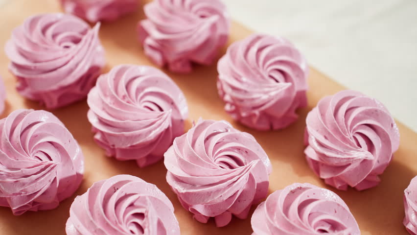 Close up of creamy swirl pink cupcakes neatly arranged on brown baking paper, showcasing smooth texture, elegant piping, and vibrant pastel color