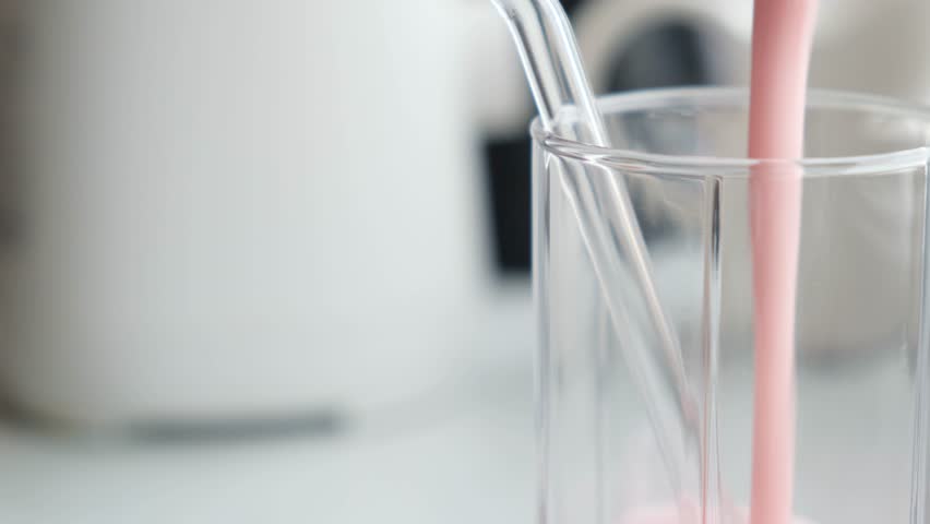 Glass transparent cup slowly filled with milk yogurt with berries. Natural homemade homemade yogurt with strawberries and raspberries. Reusable cup and glass drinking straw