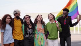 Diverse group of amused young people wave a rainbow flag walking down the city street. Joyful friends celebrating the pride month holiday with the symbol of the LBGT community. - Powered by Shutterstock - Get 15% off with code: PIKWIZARD15