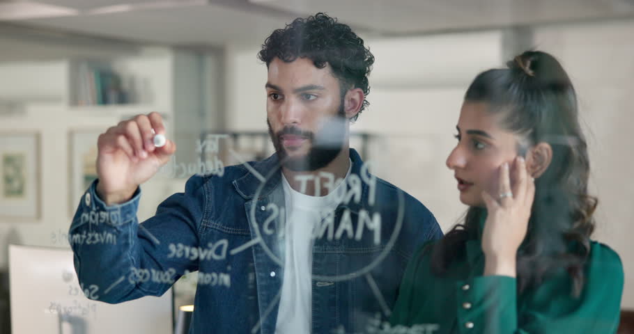 Business people, writing or planning with glass board for brainstorming, mindmap or profit margins. Businessman, woman or colleagues taking notes with graph, chart or ideas together at workplace