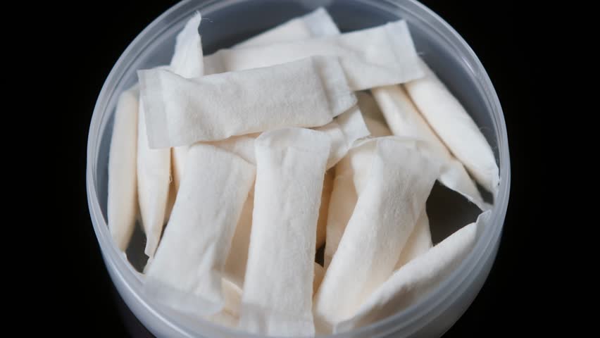 Snus nicotine tobacco close up, pack of tobacco for gum. unhealthy addiction. Man opening box with snus and taking one. 
