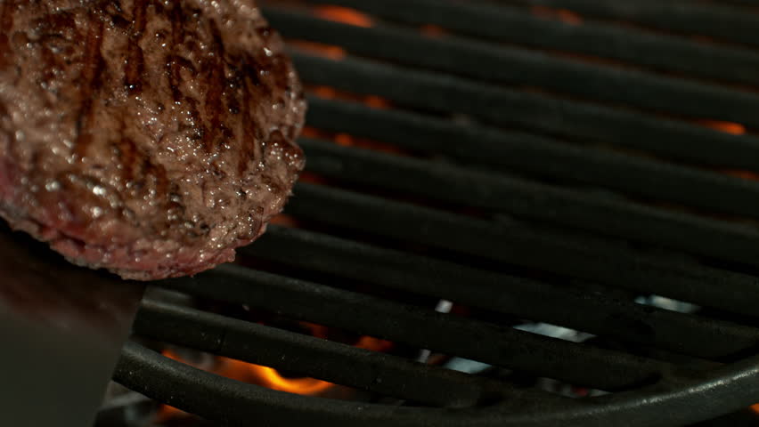 Super Slow Motion Shot of Flipping Hamburger Meat on Hot Grill with Flames and Embers at 1000fps.