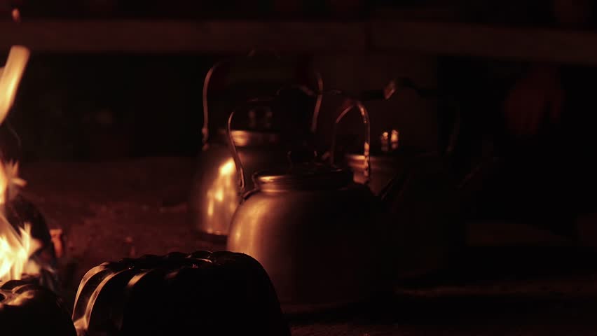 Fireplace, wood fire cooking, boiling teapots reflecting light flicker, warmth inside a finnish shelter hut in winter