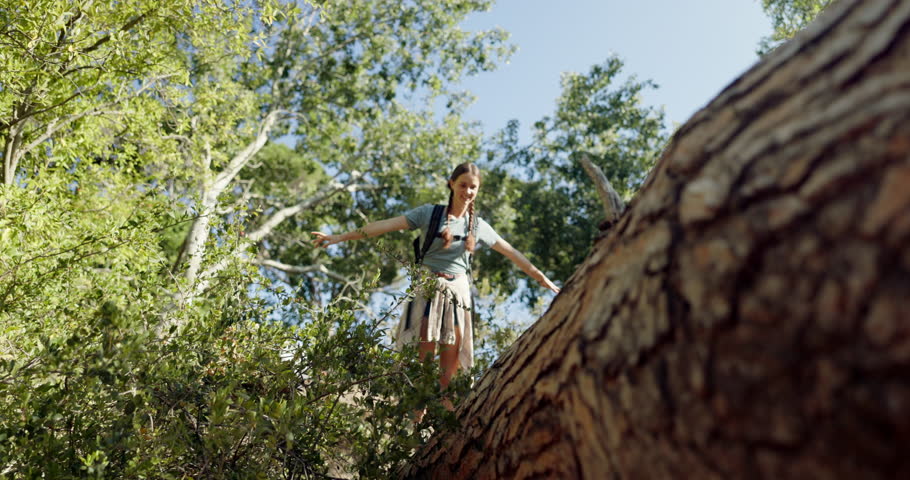 Happy woman, walking and log with balance for hiking adventure, trail or extreme trip in nature. Female person, hiker or journey with smile or backpack on tree for trekking path in forest or woods