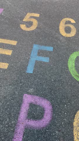 alphabet and numbers are drawn with color paint on a children's asphalt playground to learn and play. the alphabet educational element learning space. Vertical video