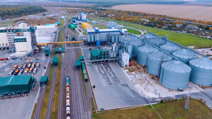 Modern agricultural enterprise with railways across it. Large silo tanks for grain storage in the rural area. Aerial view.
