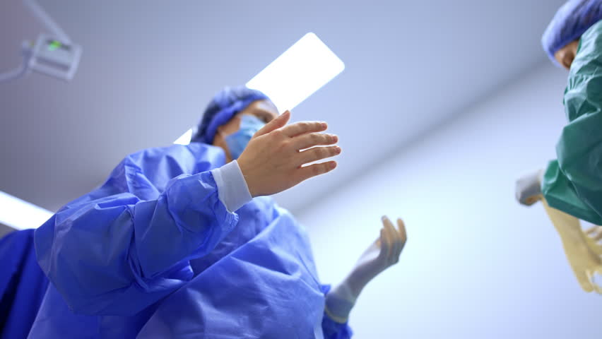 Nurse takes latex gloves and helps the doctor to wear them. Surgeon's preparation before operation. Low angle view. - Powered by Shutterstock - Get 15% off with code: PIKWIZARD15