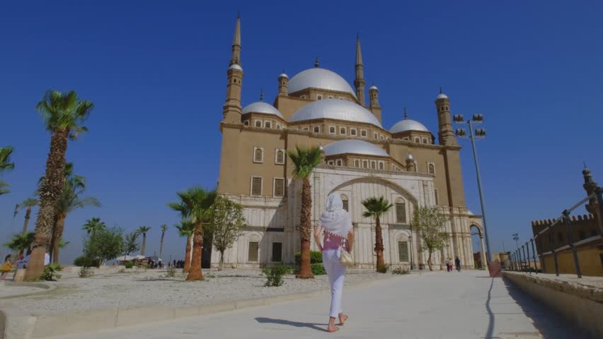 Woman walking toward a grand mosque in Cairo, Egypt.