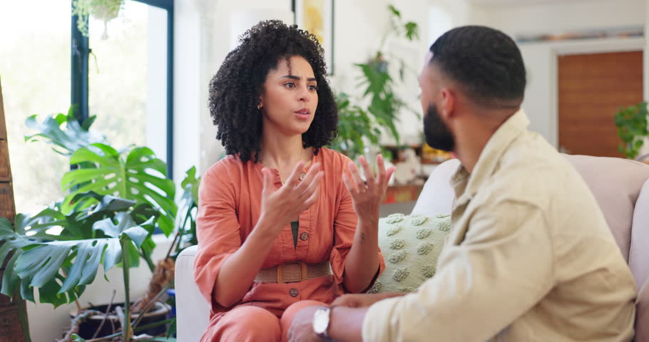 Couple, sofa and argument with fight in home with discussion, cheating or anger in living room. Man, woman and conflict with talking on couch, lounge and apartment with frustrated face in Colombia