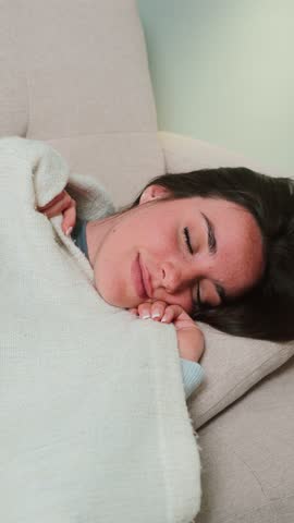 Young woman peacefully sleeping on a cozy couch, embracing tranquility and serenity in a moment of rest and relaxation, enjoying a deep slumber while lost in dreams and comfort during a quiet