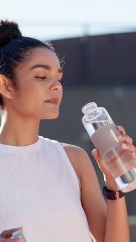 Girl, drinking water and bottle at tennis court for sport, hydration and break in summer for workout. Person, woman and athlete with liquid, rest and tired at training for competition in Colombia