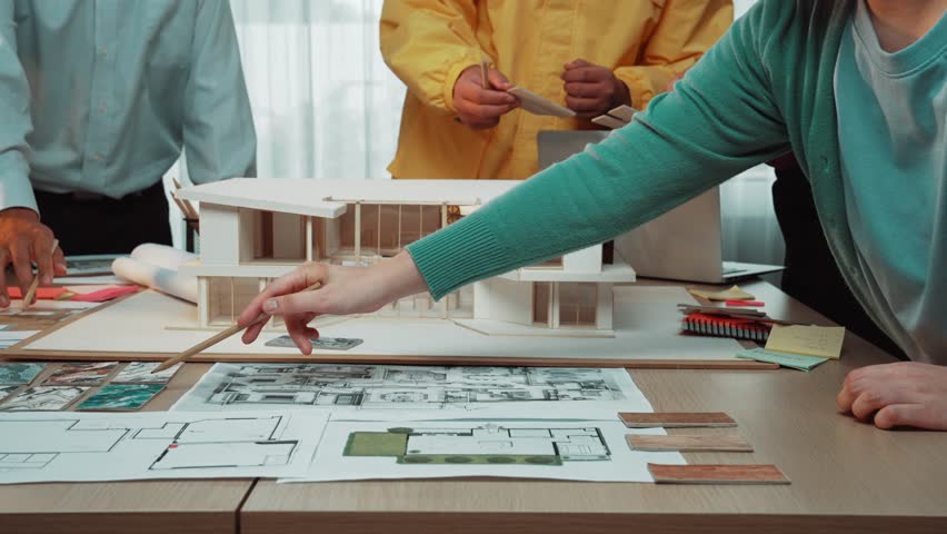 A professional team of architects engages in a collaborative building project, surrounded by blueprints, planning tools, and a detailed 3D model, fostering creativity and teamwork. SACTR - Powered by Shutterstock - Get 15% off with code: PIKWIZARD15