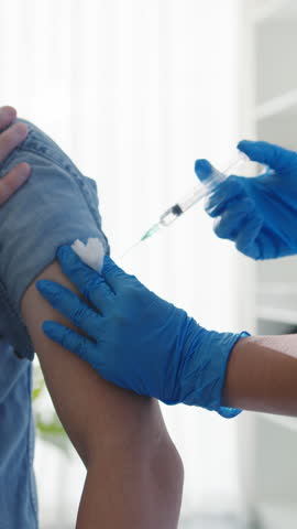 Vertical Screen : Young Asia lady nurse giving flu antivirus vaccine shot to senior male patient wear face mask protection from virus disease at health clinic or hospital office. Vaccination concept.