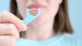 Young woman brushing teeth with disposable dental floss close-up front view on blue background. - Powered by Shutterstock - Get 15% off with code: PIKWIZARD15