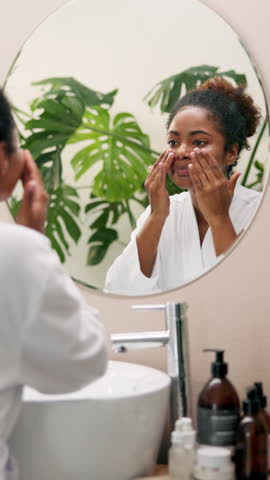 Beauty, mirror or woman with cream application for anti aging treatment, hyaluronic acid or morning routine. Reflection, african person or spf sunscreen for skin maintenance or face hydration in home