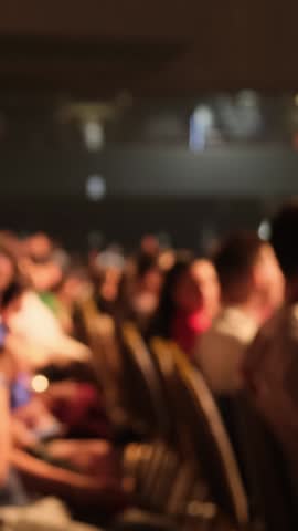 Blurred panoramic view of people sitting on chairs in the auditorium, listening to a business coach and performing various tasks