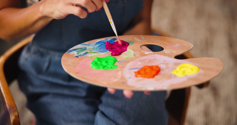 Hands, painter and palette in home studio with color, mix and creative process, tools and talent for project. Person, artist and wood tray with brush, equipment and hobby with painting at apartment