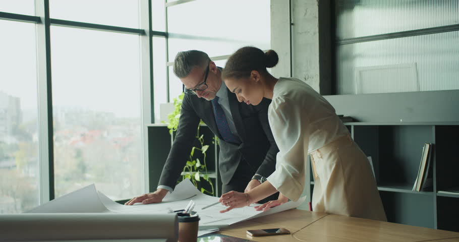 Focused team examining floor plan in bright office