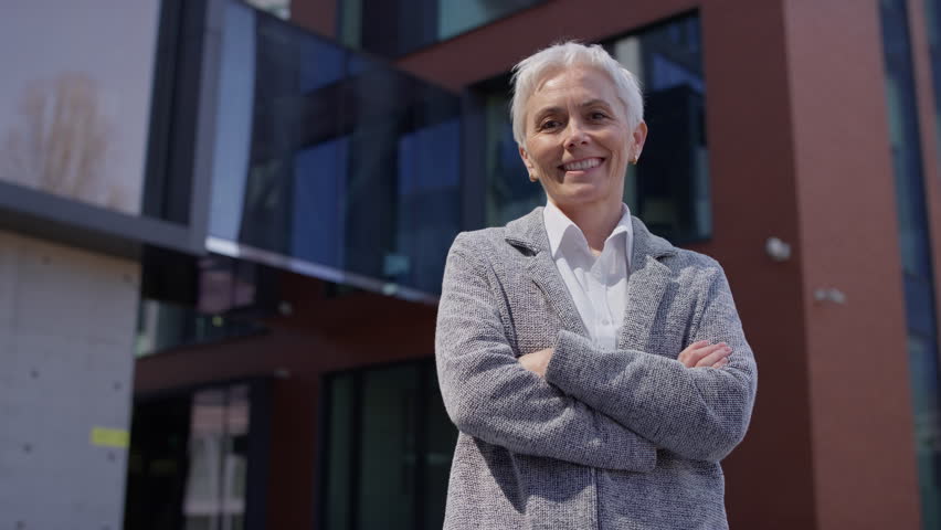 Confident senior businesswoman standing outside modern office building