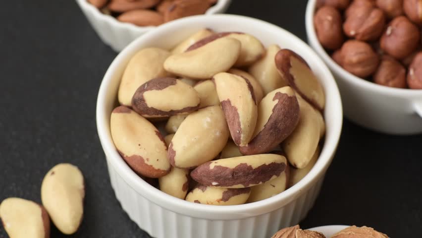 Brazil nut kernels in ceramic bowl on dark concrete background